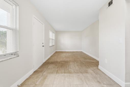 A room with a tiled floor and a window with blinds.