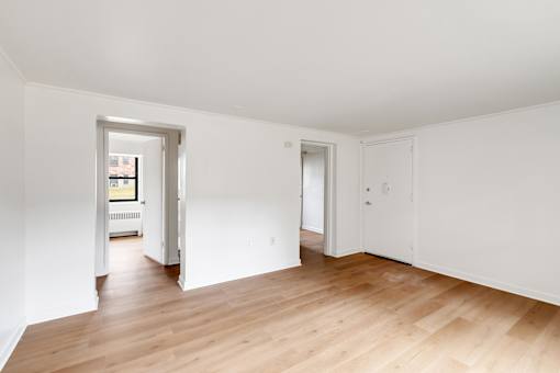 A room with white walls and wooden flooring with two doors.