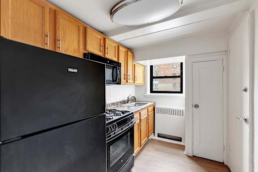 A black fridge in a kitchen with wooden cabinets.