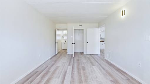 A long hallway with white walls and wood flooring.