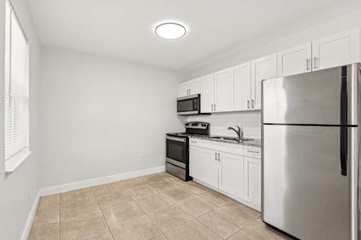 A kitchen with a refrigerator, microwave, oven, and sink.
