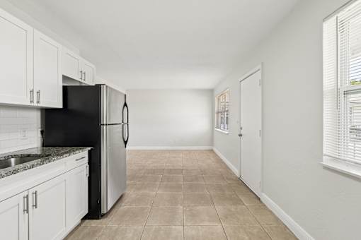 A kitchen with white cabinets and a black refrigerator.