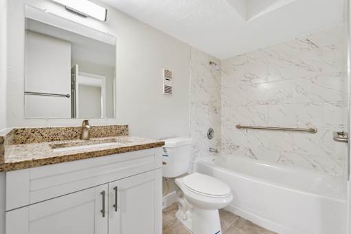 A white toilet sits in a bathroom with marble tiles.