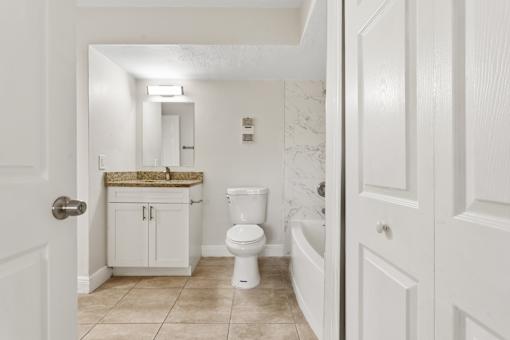A white bathroom with a toilet, sink, and bathtub.