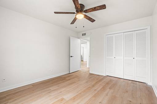A room with a ceiling fan and wooden floors.