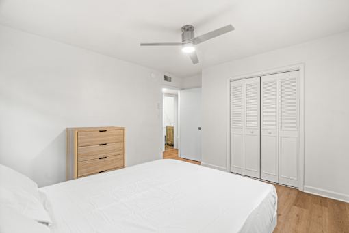 A white bedroom with a bed, dresser, and wardrobe.
