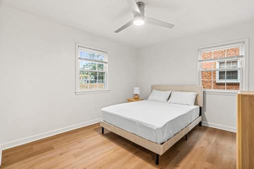 A bedroom with a bed, a ceiling fan, and a window.