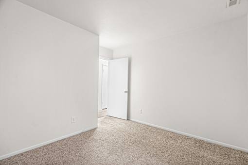 A white room with a carpeted floor and a door.