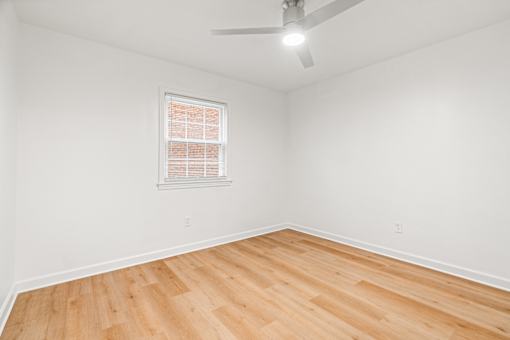 A room with a ceiling fan and a window with blinds.