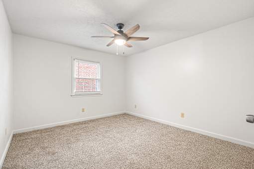 A room with a ceiling fan and carpeted floor.