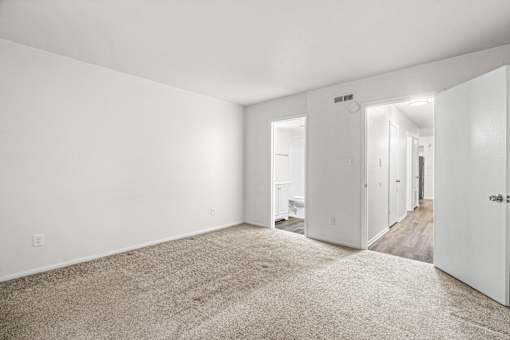 A spacious, empty room with white walls and carpeted floor.