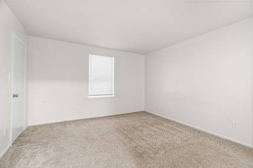 A room with a carpeted floor and a window.