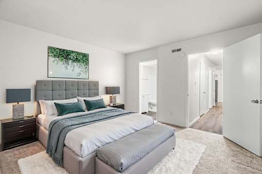 A bedroom with a large bed and a painting on the wall.