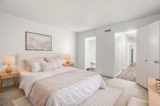 A bedroom with a large bed and two lamps on side tables.