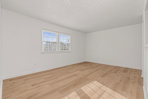 A room with wooden flooring and a window with blinds.