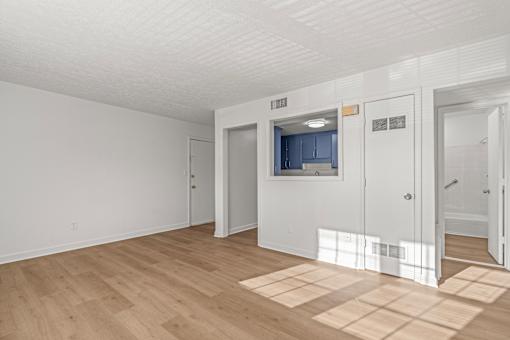 A room with white walls and wooden flooring with a door on the right.