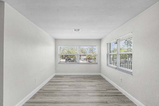 A long, empty room with a window overlooking a tree-filled street.