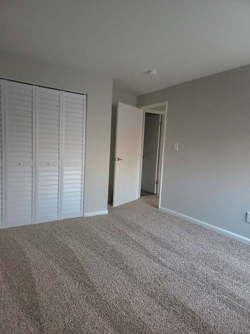 A room with a carpeted floor and a white door.