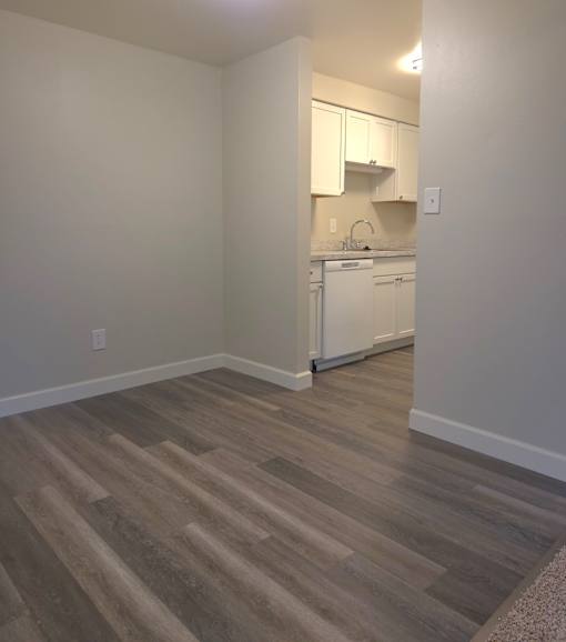 A kitchen with white appliances and wooden floors.