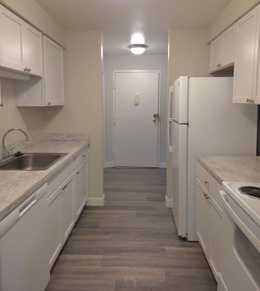A kitchen with white cabinets and a white fridge.