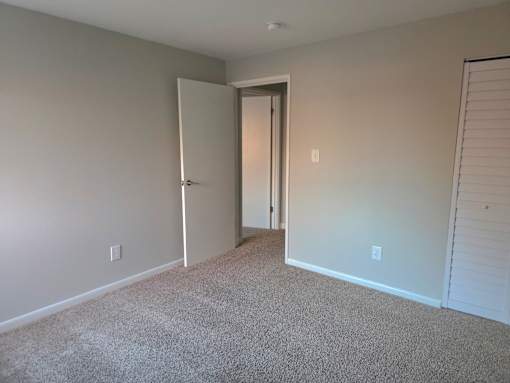 A room with a carpeted floor and a doorway leading to another room.