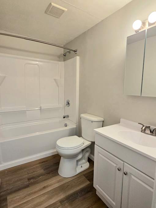 A white toilet sits in a bathroom next to a sink.