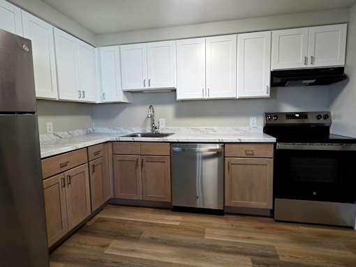 A kitchen with white cabinets and a wooden floor.