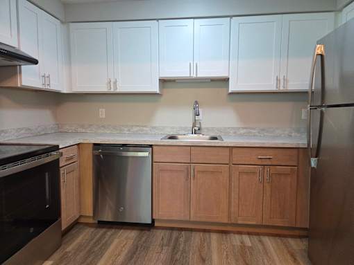 A kitchen with wooden cabinets and a stainless steel dishwasher.