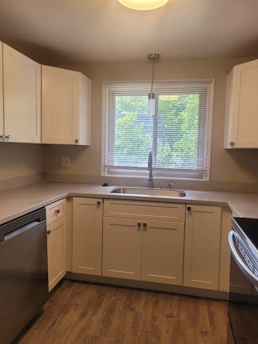 A kitchen with white cabinets and a window.