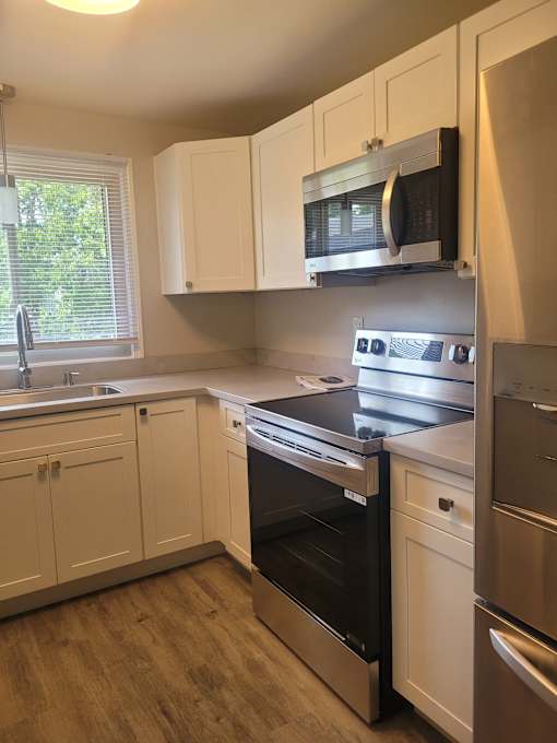 A kitchen with white cabinets and a black microwave above the stove.