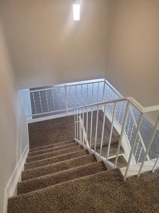 A staircase with a carpeted runner and white railings.