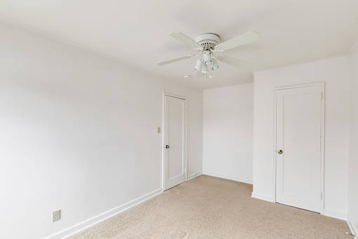 A room with a ceiling fan and two doors.