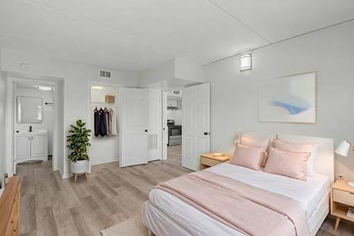 A bedroom with a bed, nightstand, and a plant.