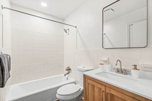 A white bathroom with a tub, toilet, sink, and mirror.