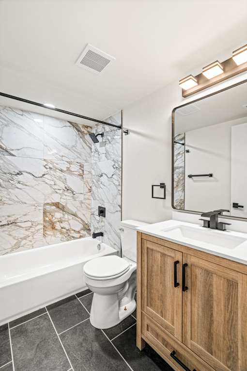 A white toilet sits in a marble bathroom.