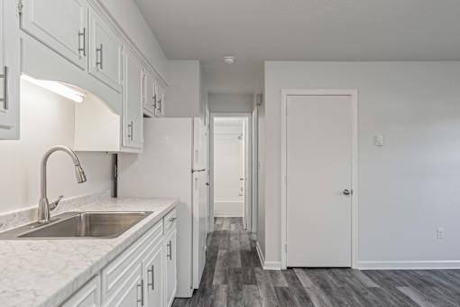 A kitchen with white cabinets and a marble countertop.