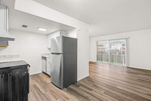 A kitchen with a black cabinet and a grey fridge.