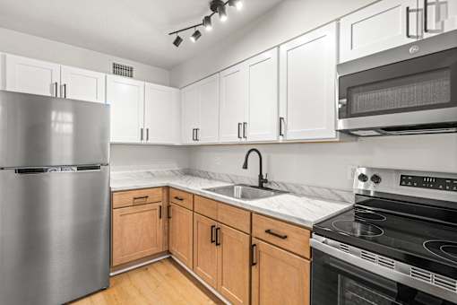 A kitchen with a stainless steel refrigerator, microwave, and oven.