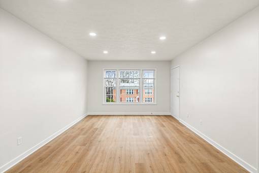 A room with wooden floors and a window showing a view of a building.
