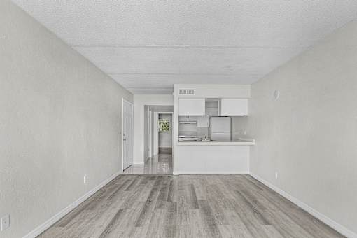 A kitchen with white cabinets and a wooden floor.