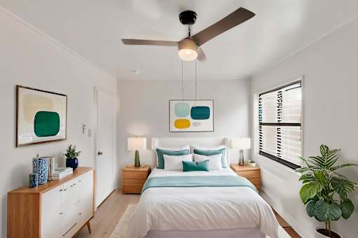 A bedroom with a bed, nightstands, and a ceiling fan.