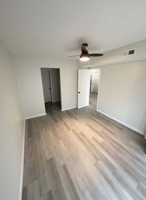 A room with a ceiling fan and a wooden floor.