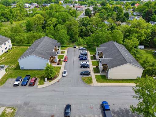 A parking lot with cars and two houses.
