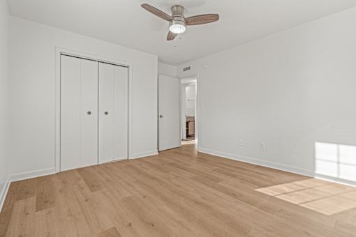A room with a ceiling fan and wooden flooring.