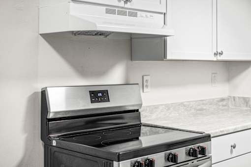 A modern kitchen with a stainless steel oven and white cabinets.