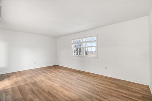 A room with a window and wooden flooring.