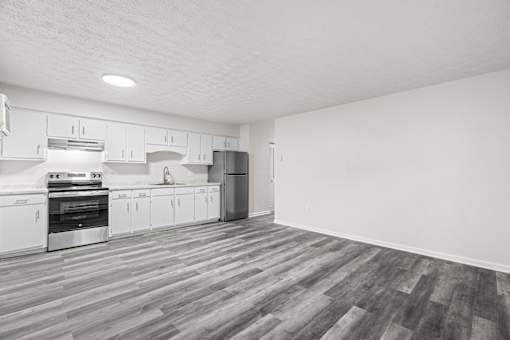 A kitchen with white cabinets and a wooden floor.