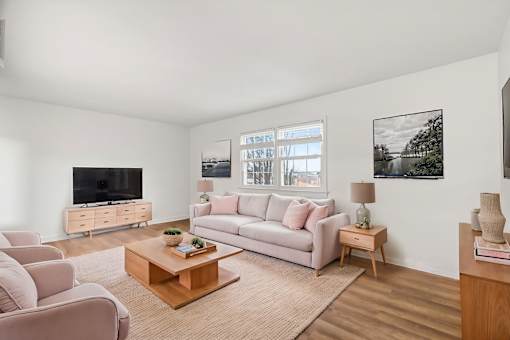A living room with a white couch, a wooden coffee table, and a television.