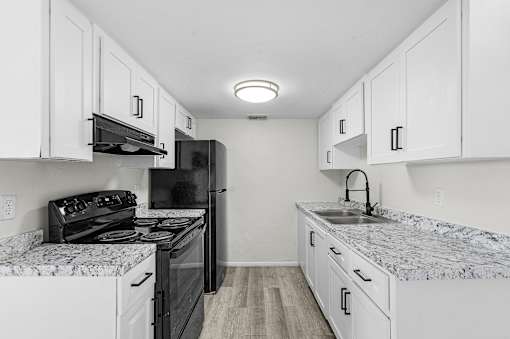 A kitchen with black appliances and white cabinets.