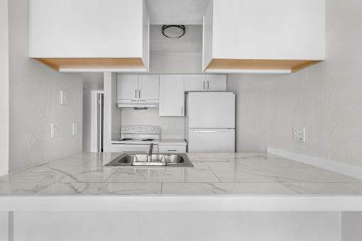 A kitchen with white cabinets and a marble countertop.